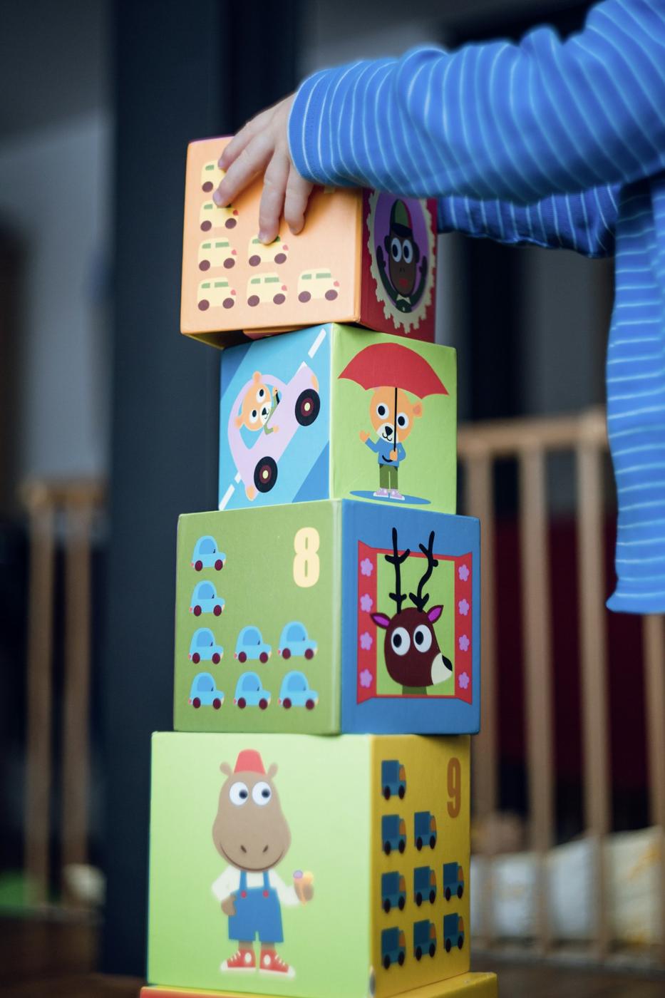 A child in a striped shirt stacks colorful blocks