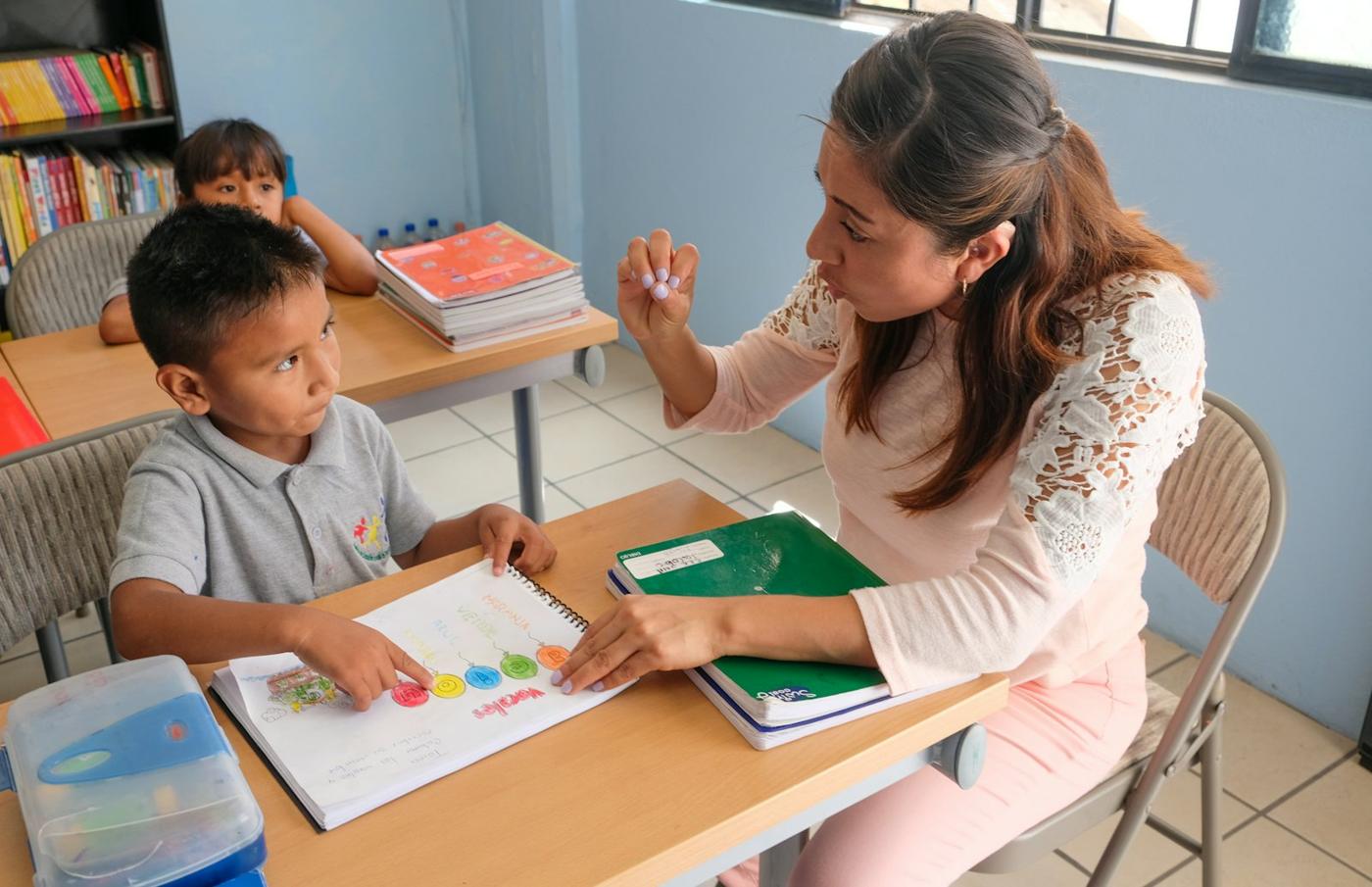 A guide points to a workbook with an elementary student